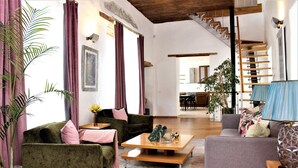 Un vaste espace de vie comprenant un ensemble de canapés, une table basse et un escalier menant à un niveau supérieur.