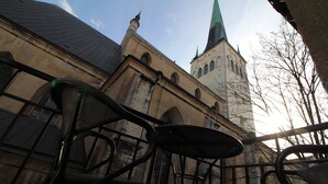 Une vue d’un bâtiment doté d’une tour et d’un balcon avec des chaises.