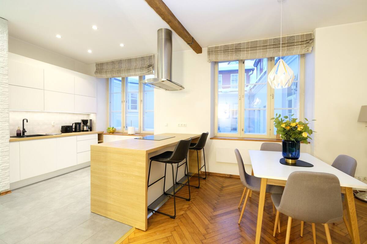 Une cuisine moderne dotée d’un îlot central, de tabourets de bar et d’une table à manger avec des chaises.