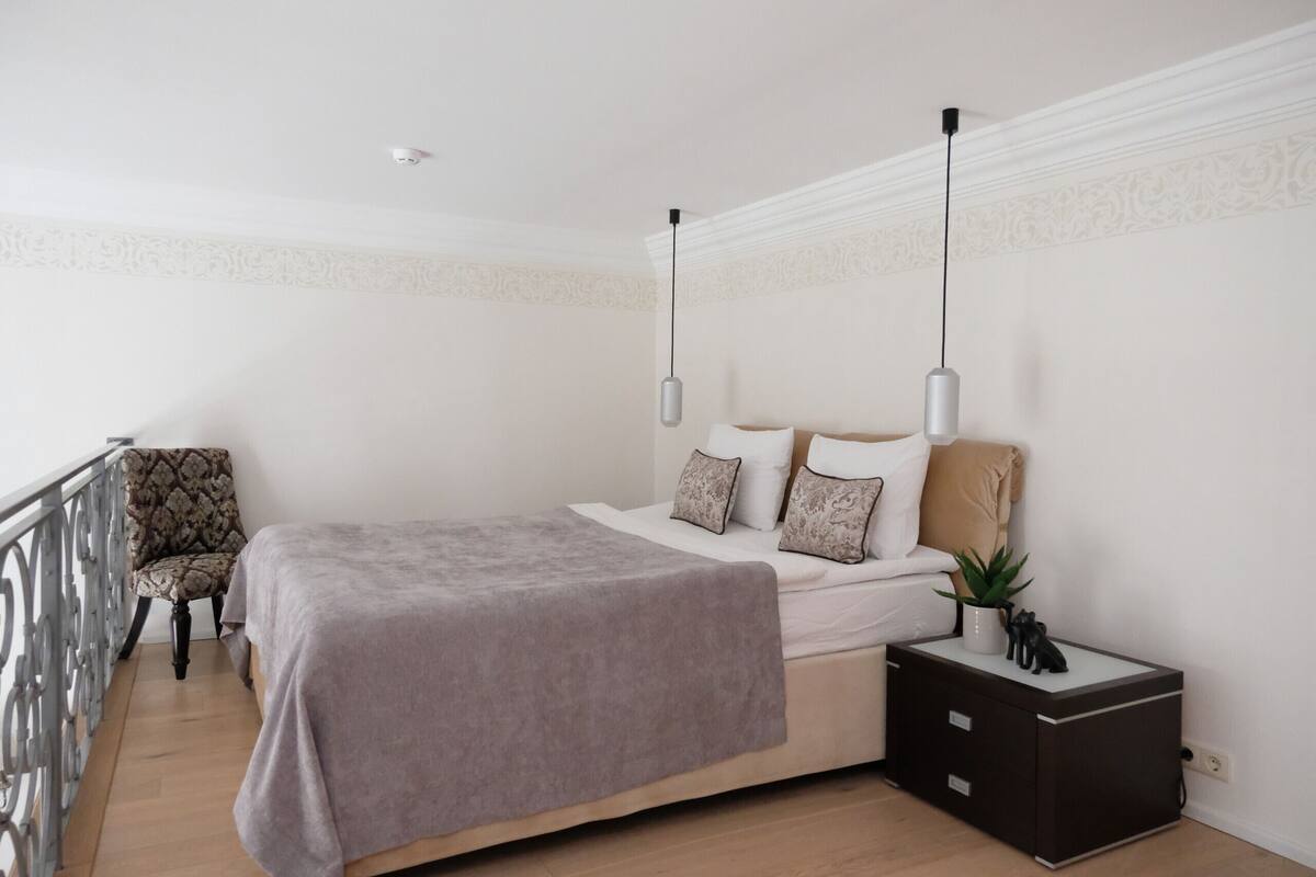Une chambre à coucher avec un lit, des tables de chevet, une chaise et un balcon.