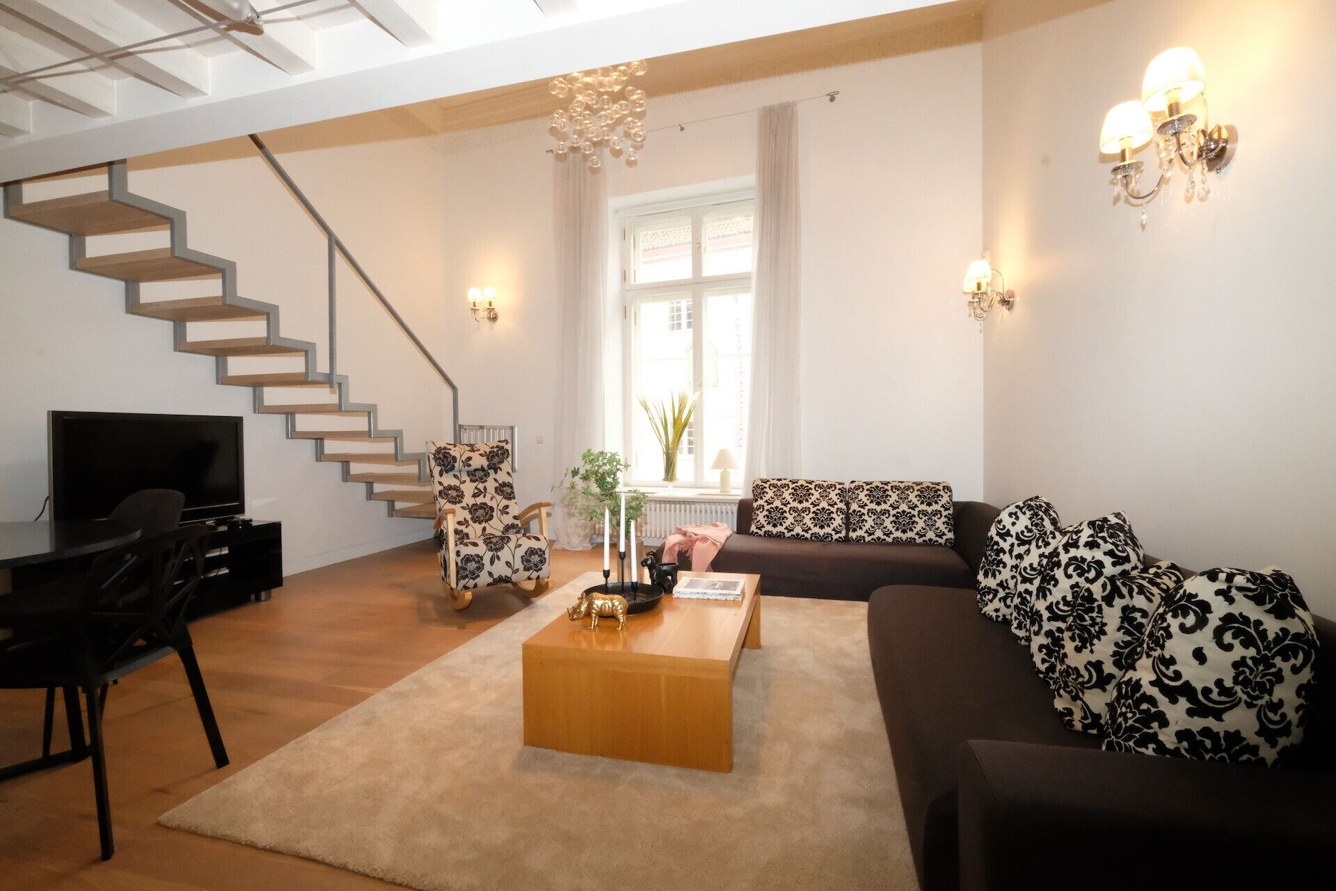 A modern living room with a staircase, a sofa, a coffee table, and a TV.
