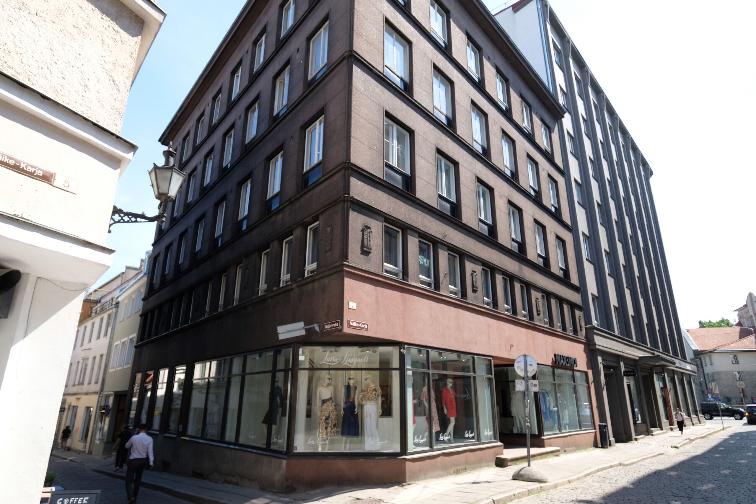 Un edificio de varios pisos con un local comercial en la planta baja, con amplios ventanales de vidrio que exhiben maniquíes.