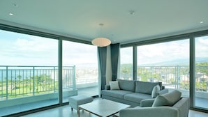 Un salón amplio con un balcón grande, un sofá, una mesa de centro y vistas a la ciudad.