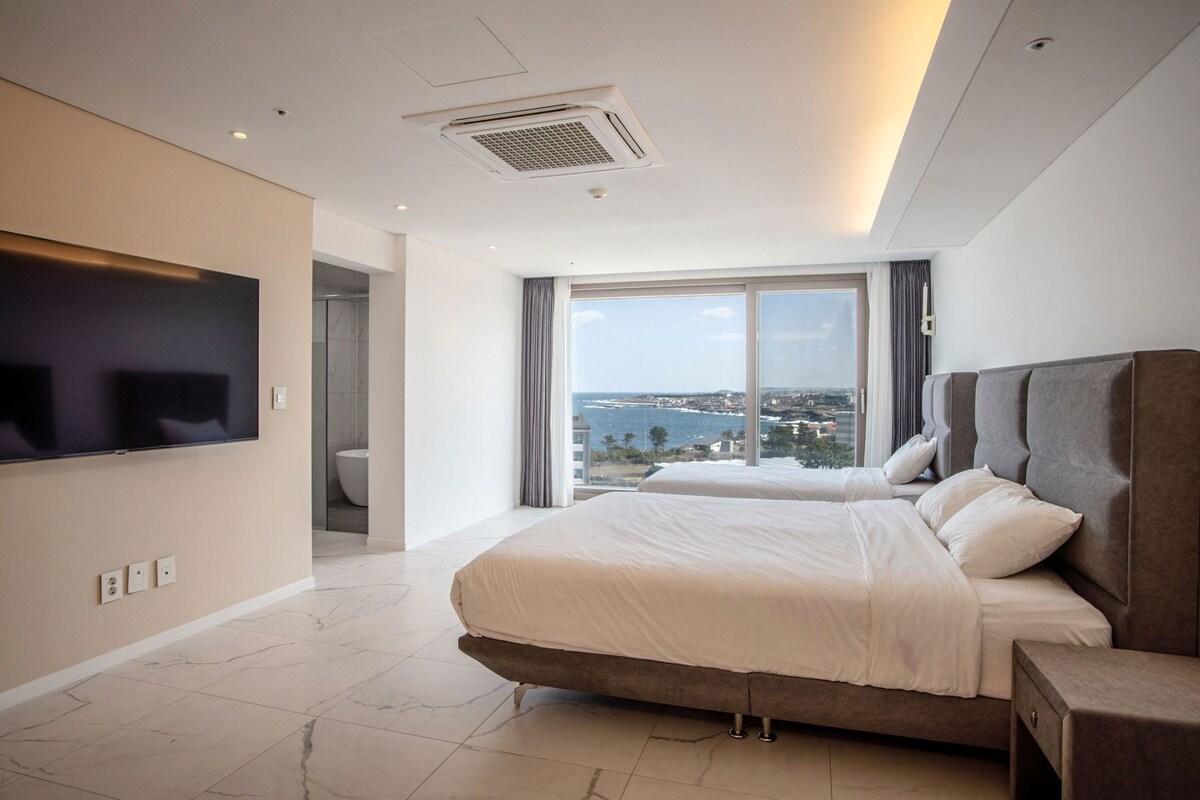 Une chambre d’hôtel moderne avec un grand lit, une télévision et une vue sur la mer.