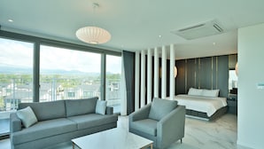 Una habitación de hotel moderna con un ventanal grande, un sofá, una silla, una cama y un piso de mármol.