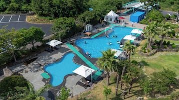 An aerial view of a resort with multiple swimming pools, a covered pavilion, and a parking area.