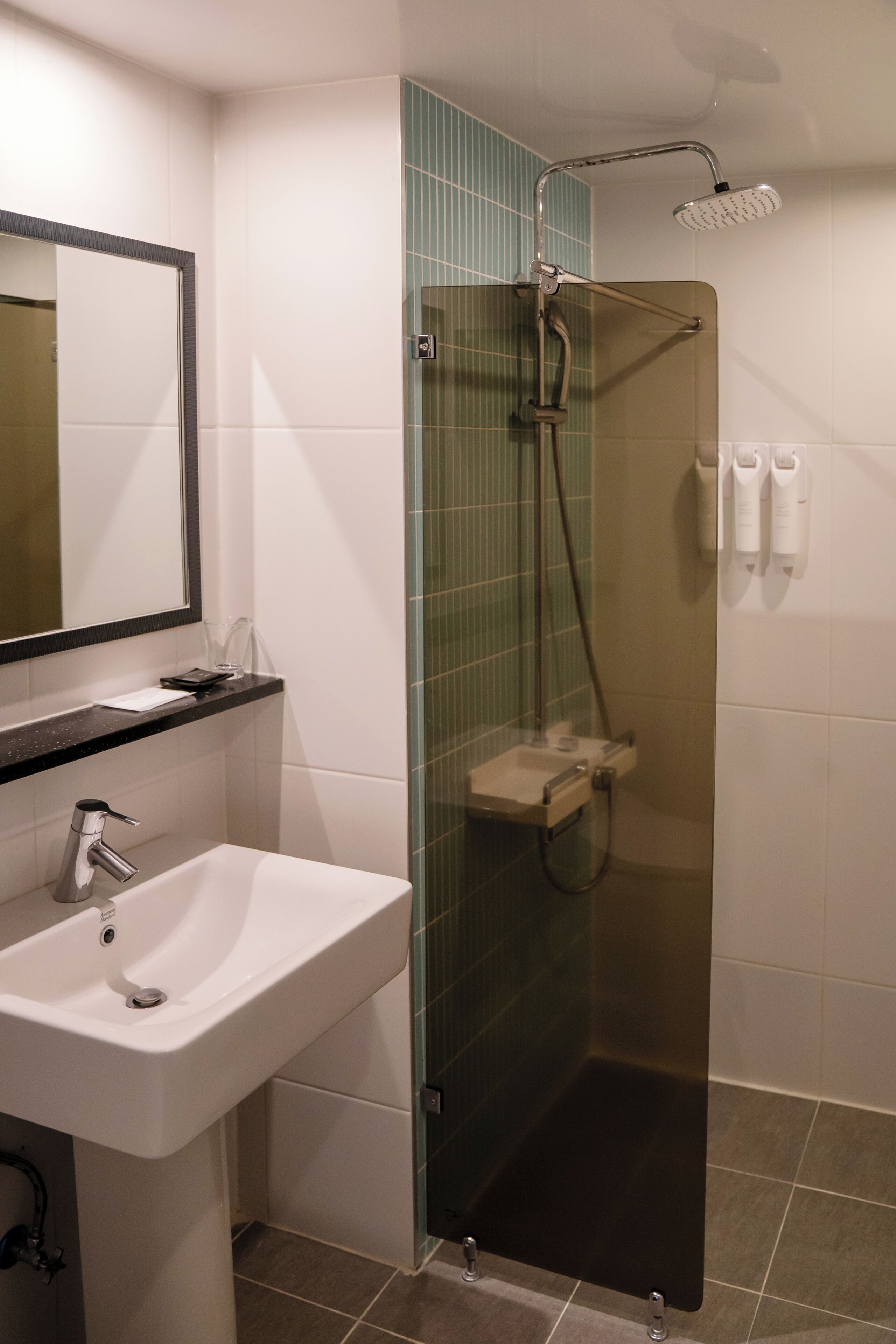 Une salle de bain moderne avec une douche à parois de verre, un lavabo blanc et un miroir au-dessus.