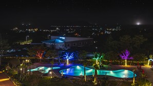 A resort with multiple swimming pools, a large building labeled "MALLIN RESORT," and a cityscape in the background. - Hallim Resort (Jeju City)