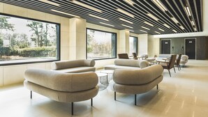 A modern lobby with sofas, a coffee table, and a view of the outdoors. - Hallim Resort (Jeju City)