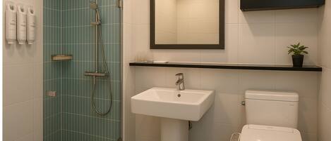 A bathroom with a shower, sink, and toilet, featuring teal tiles and a black shelf.