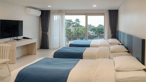 A hotel room with two beds, a desk, a TV, and a large window with a view of trees. - Hallim Resort (Jeju City)