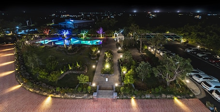 Un área ajardinada con piscina, senderos y aparcamiento de noche.