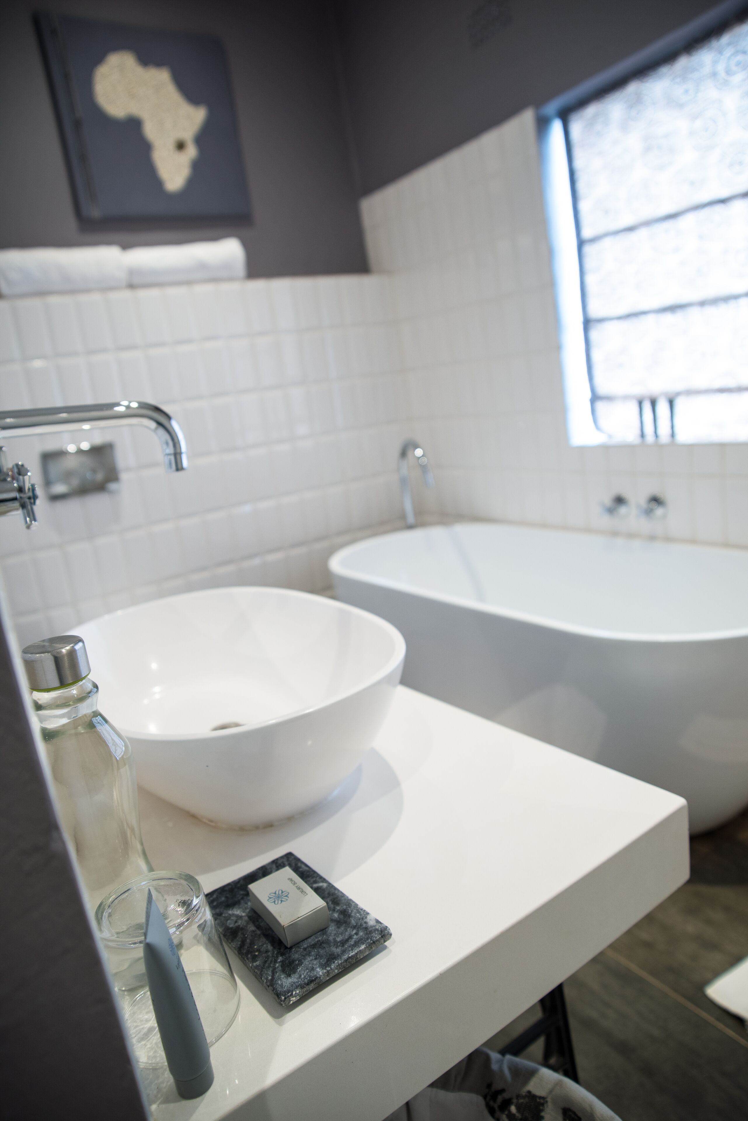 Un baño con lavamanos blanco, bañera y ventana que proporciona luz natural.