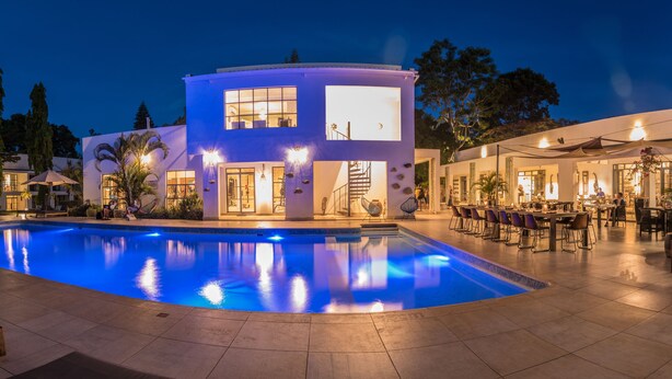 Un edificio moderno con piscina, zona de estar al aire libre y bar.