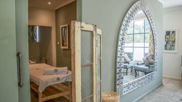 Relax in a serene space with a large arched mirror, a comfortable bed, and a stylish chair.
