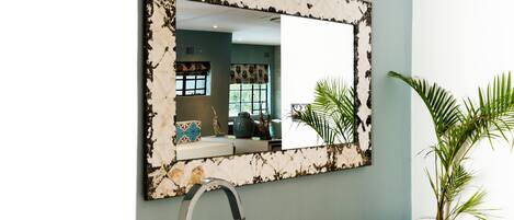 Un baño moderno con una bañera blanca, un espejo grande con marco decorativo y una planta en maceta.
