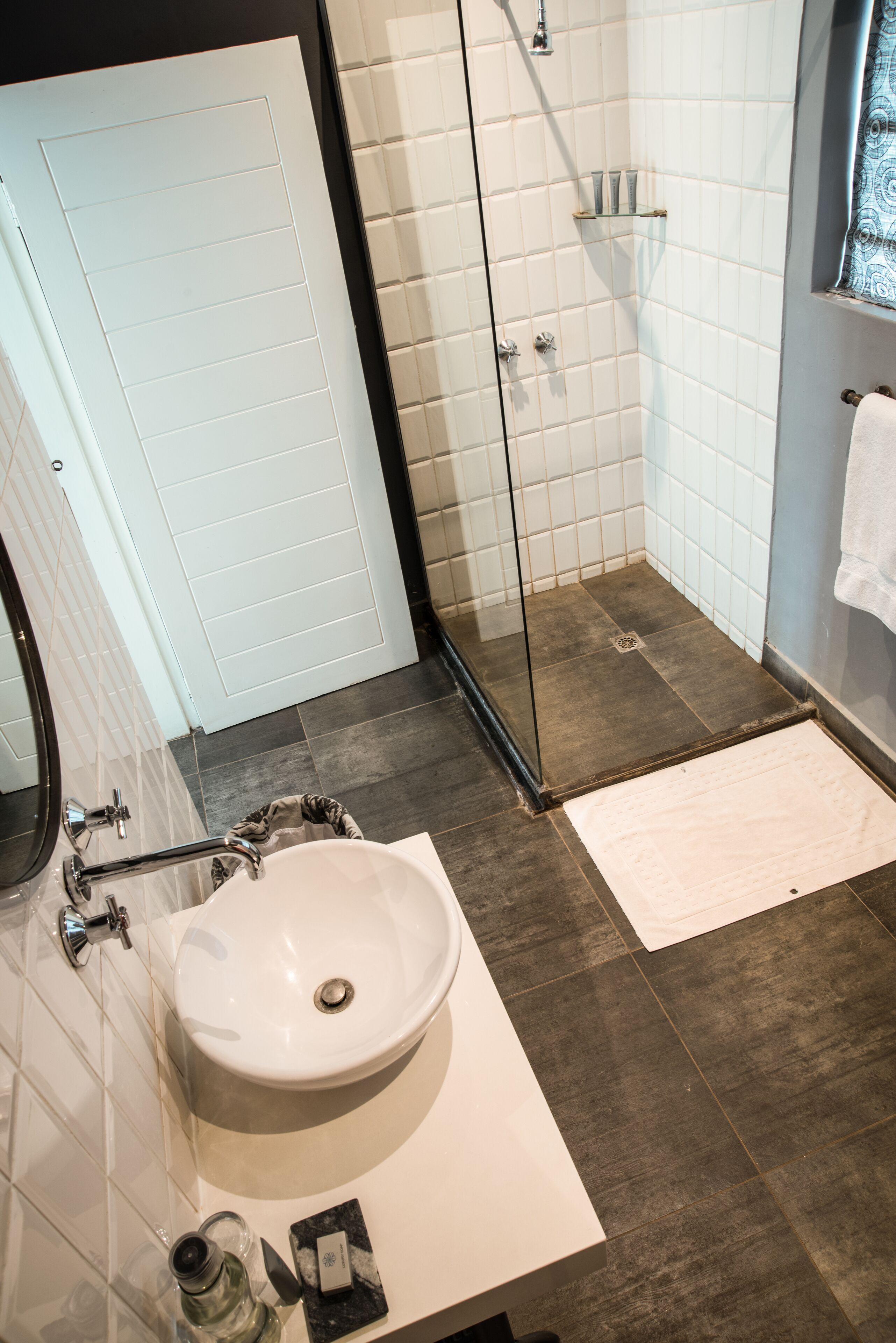 A bathroom with a white sink, a glass shower enclosure, and a white towel hanging on the wall.