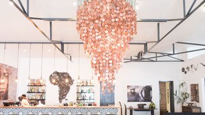 Un área de estar moderna con un bar, asientos y una lámpara colgante original.