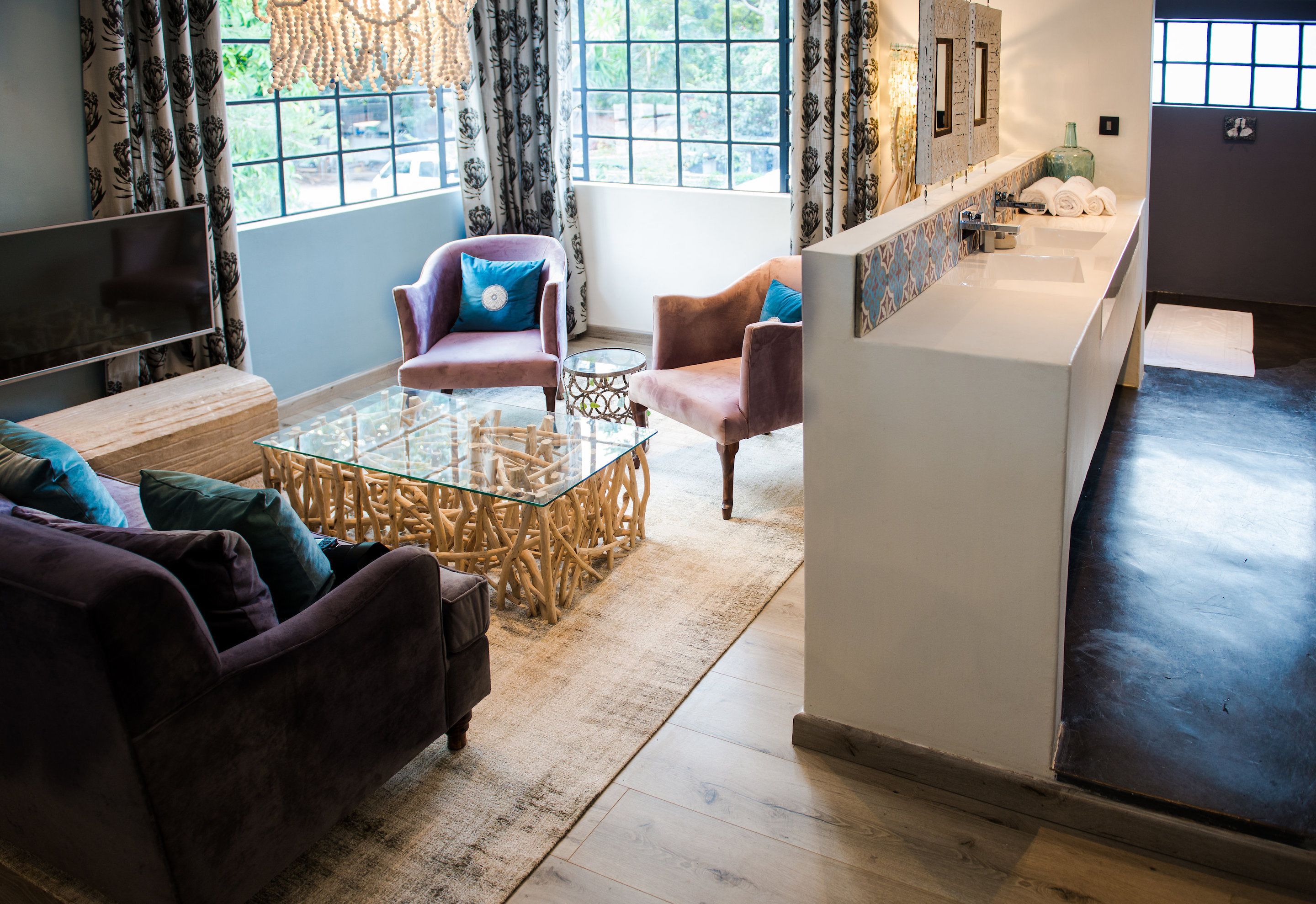 A modern living room with a glass coffee table, two sofas, and a television.