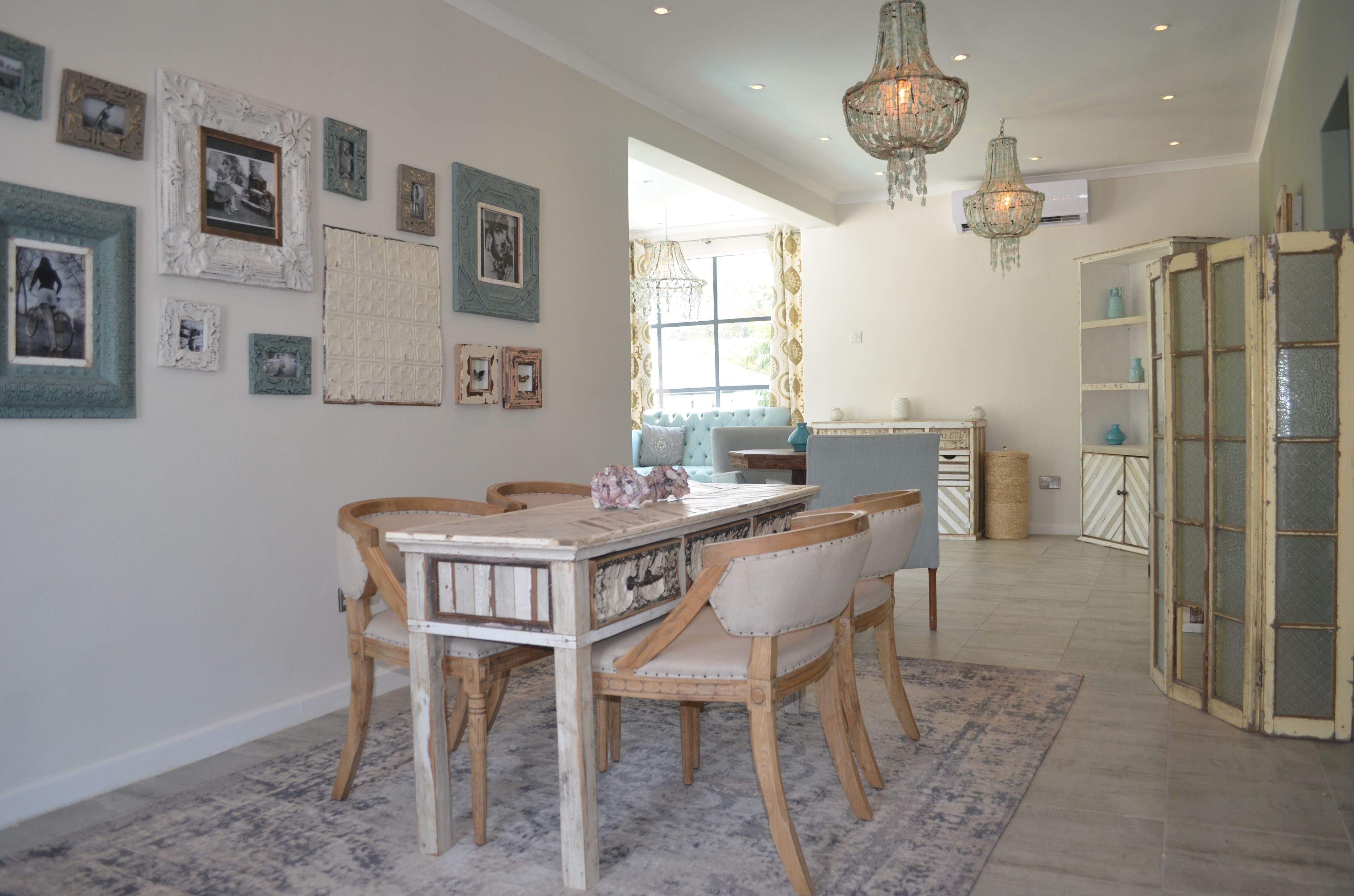 A dining area with a wooden table and chairs, surrounded by framed pictures on the walls.
