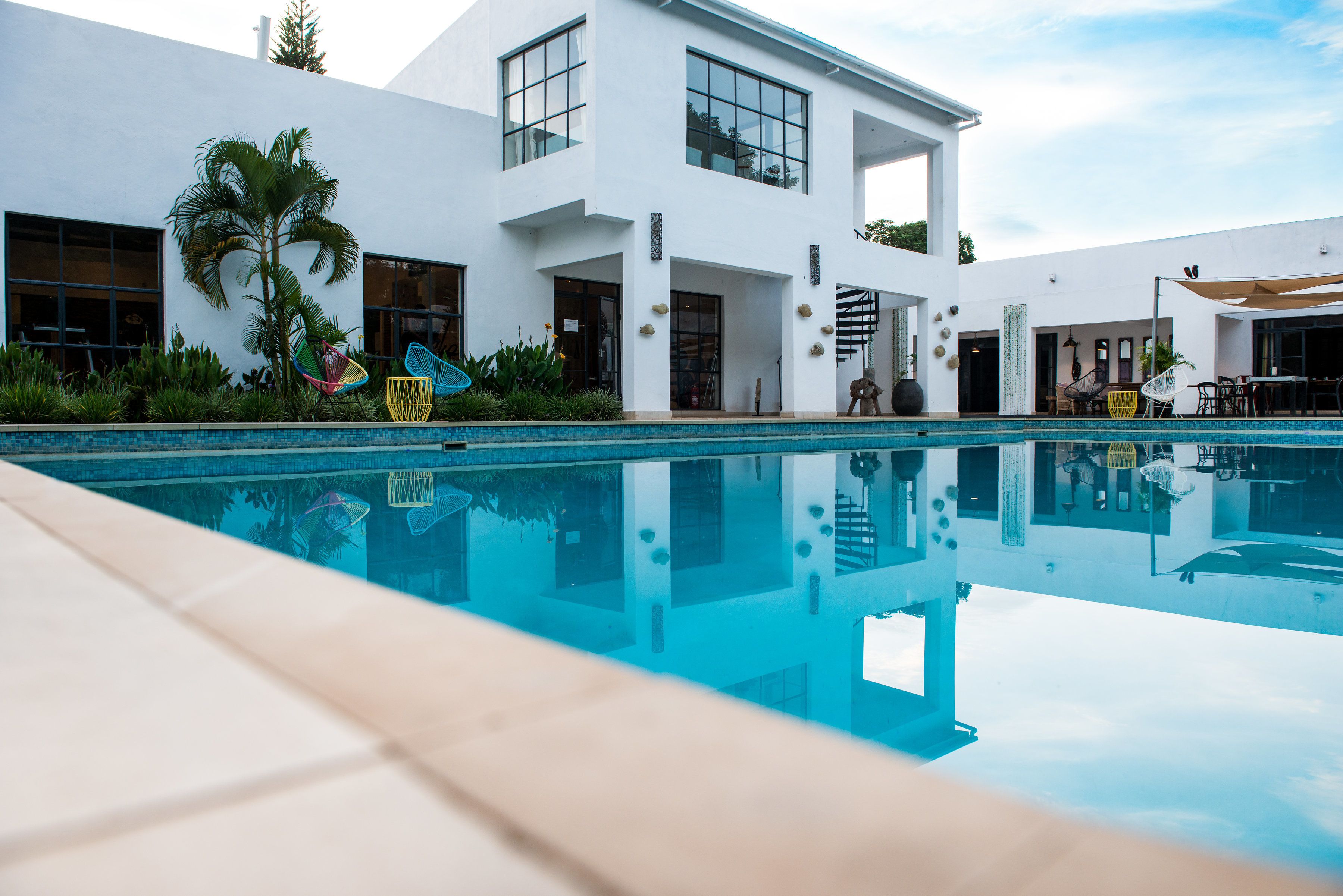 Una casa moderna con piscina, ventanas amplias y mobiliario exterior.