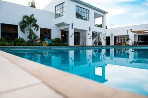 Una casa moderna con piscina, ventanas amplias y mobiliario exterior.