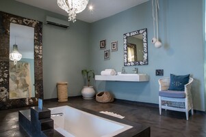 Casa de banho moderna com uma banheira grande, um lavatório branco e um espelho com moldura decorativa.