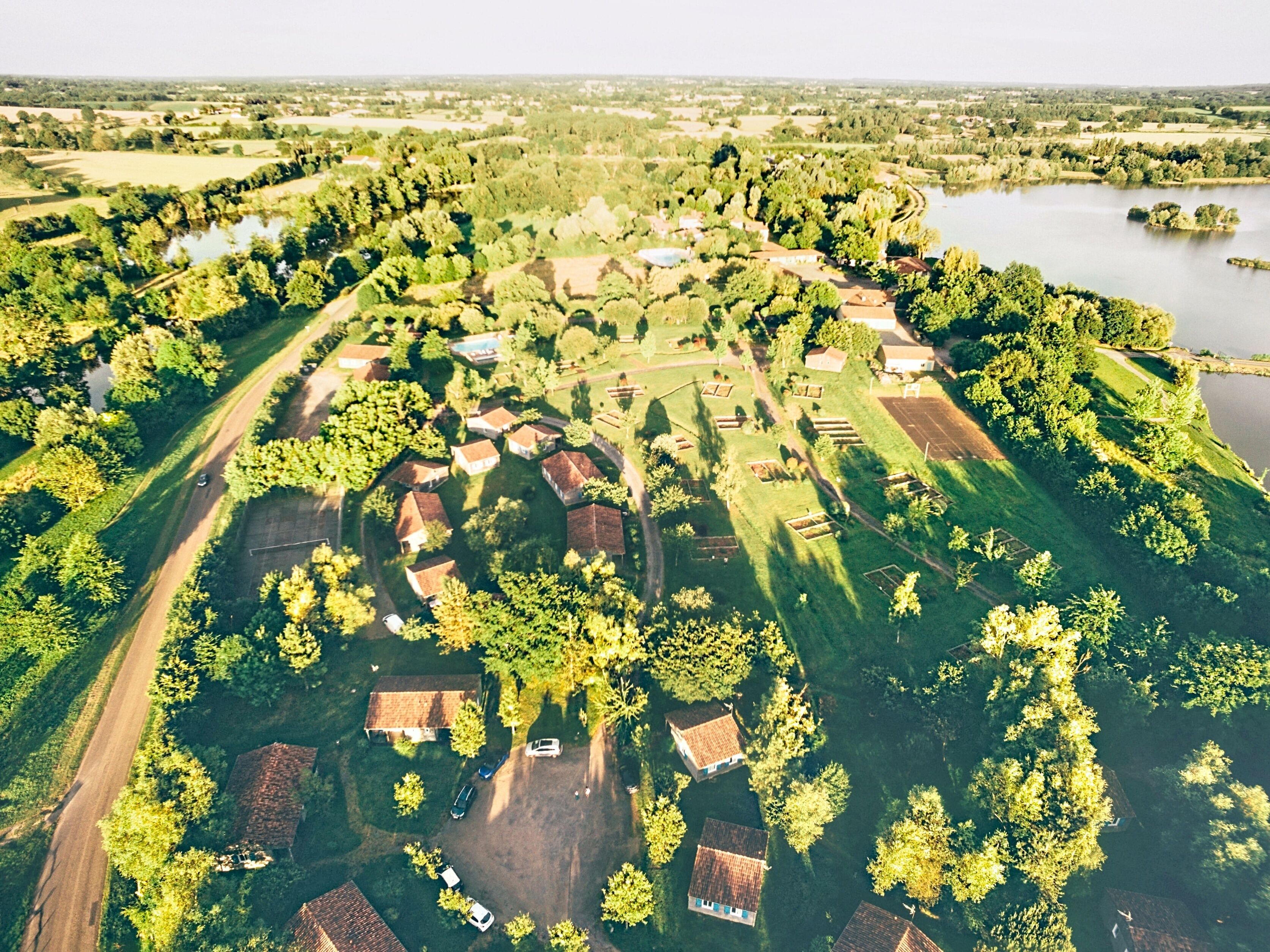 An aerial view of a residential area with houses, a road, and a body of water.