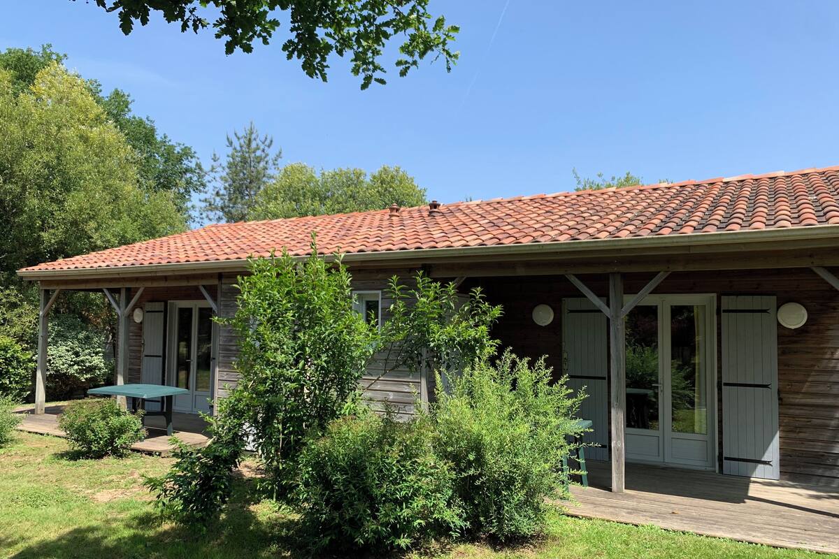 A wooden house with a tiled roof, a covered patio, and a small garden area.
