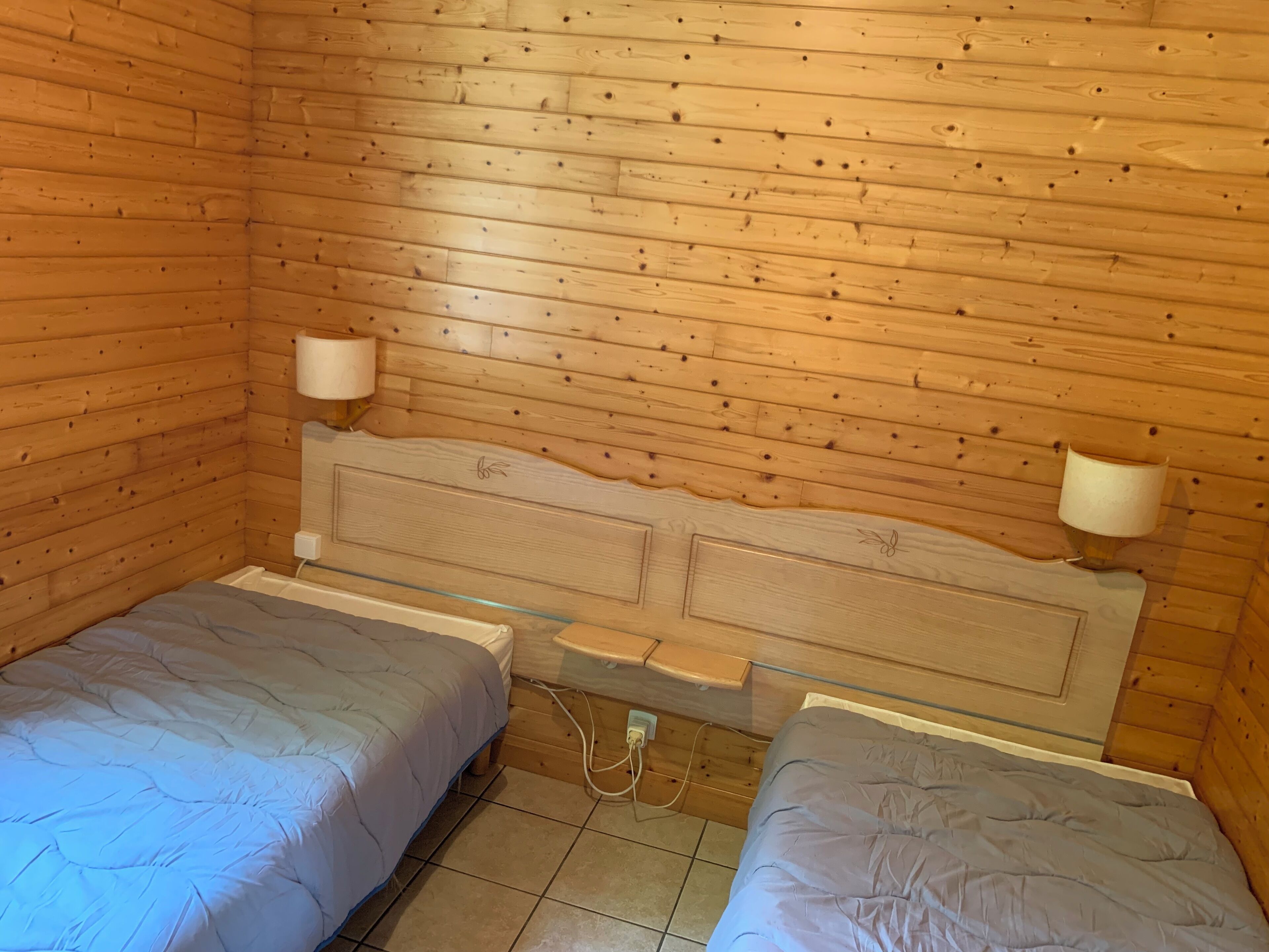A small, cozy room with wooden walls and a simple bed setup.