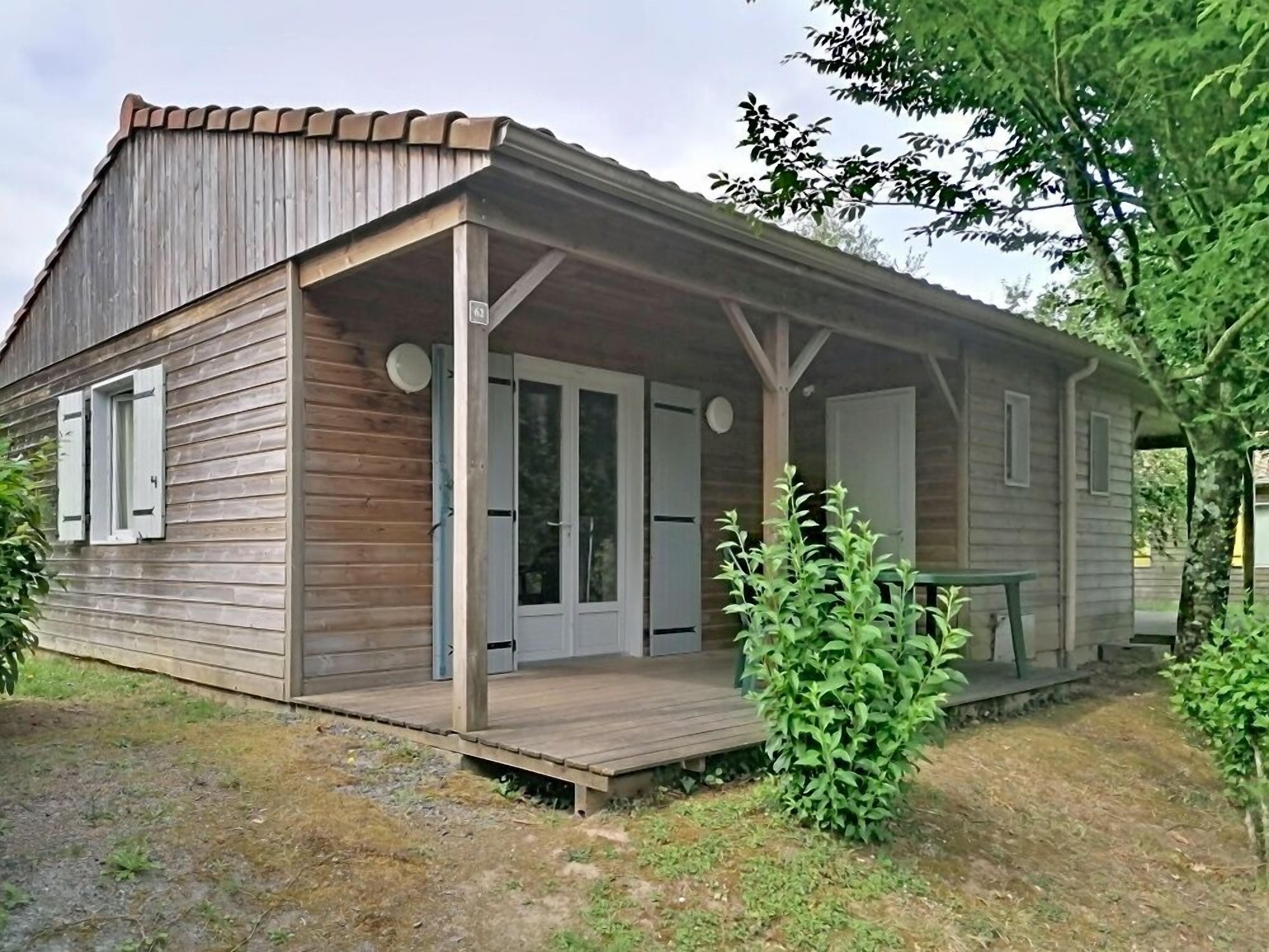 Une cabane en bois avec une véranda, une porte et une petite table.
