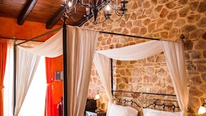 A four-poster bed with a yellow bedspread, a stone wall, and a chandelier. - Acronafplia Pension A (Nafplio)