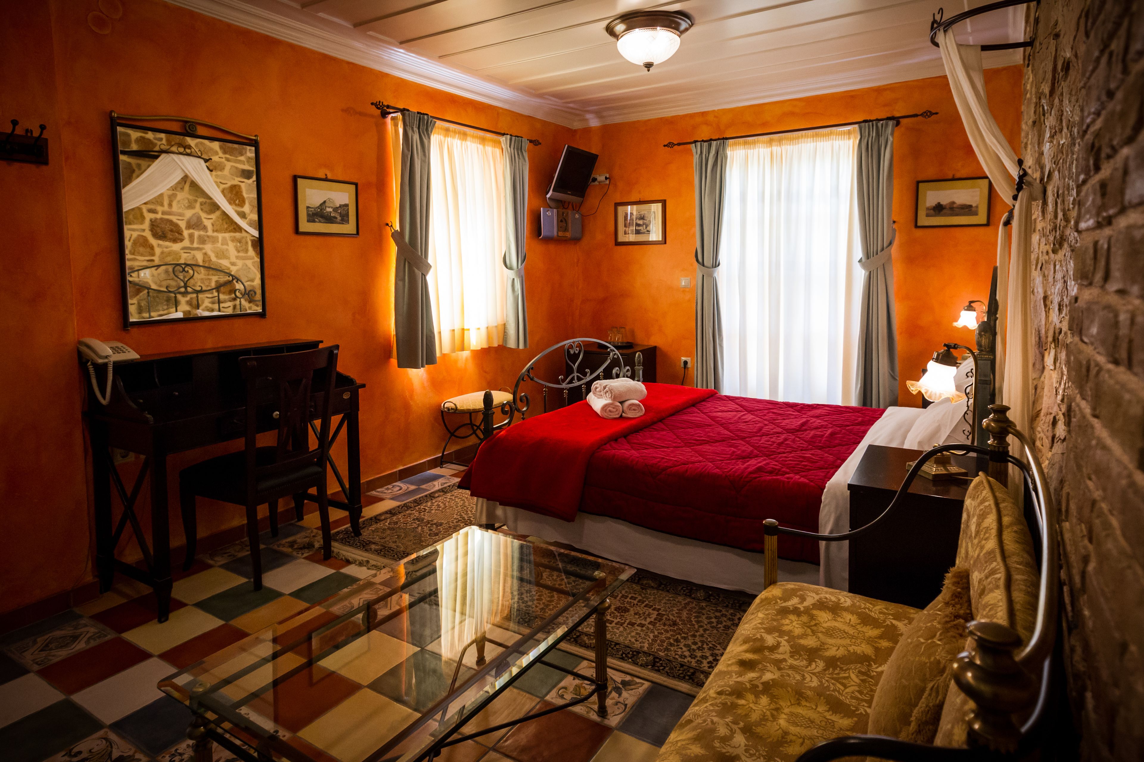 A room with a bed, a desk, a chair, a table, and a lamp.