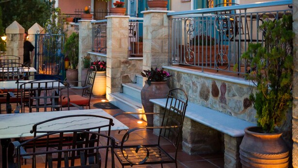 An outdoor seating area with stone pillars, metal railings, and tables and chairs. - Acronafplia Pension A (Nafplio)