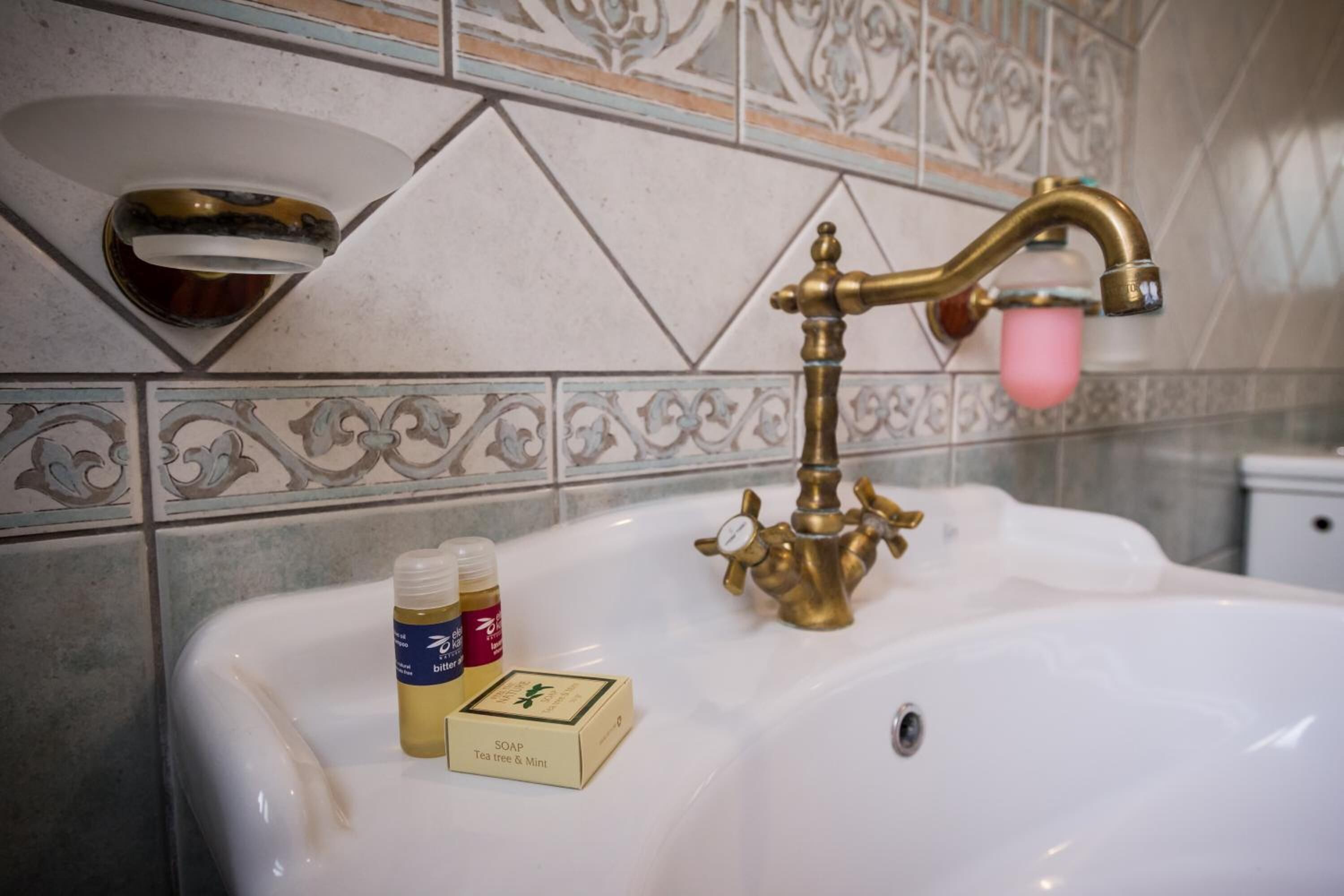 A bathroom sink with a gold faucet and a soap dispenser.
