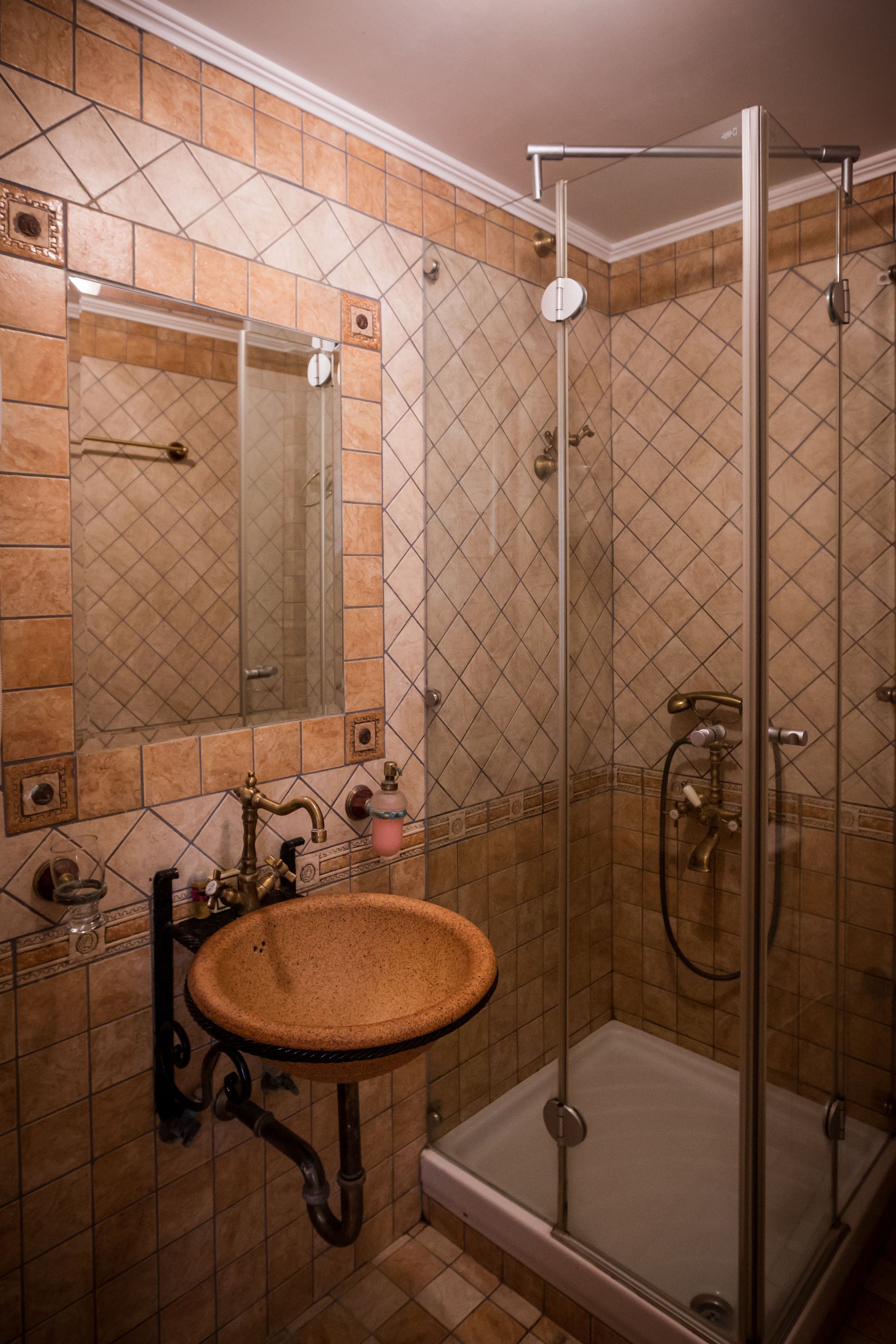 A bathroom with a glass-enclosed shower, a sink with a decorative basin, and a mirror above the sink.