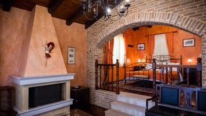 A cozy room with a fireplace, a staircase leading to a bedroom, and a chandelier. - Acronafplia Pension A (Nafplio)