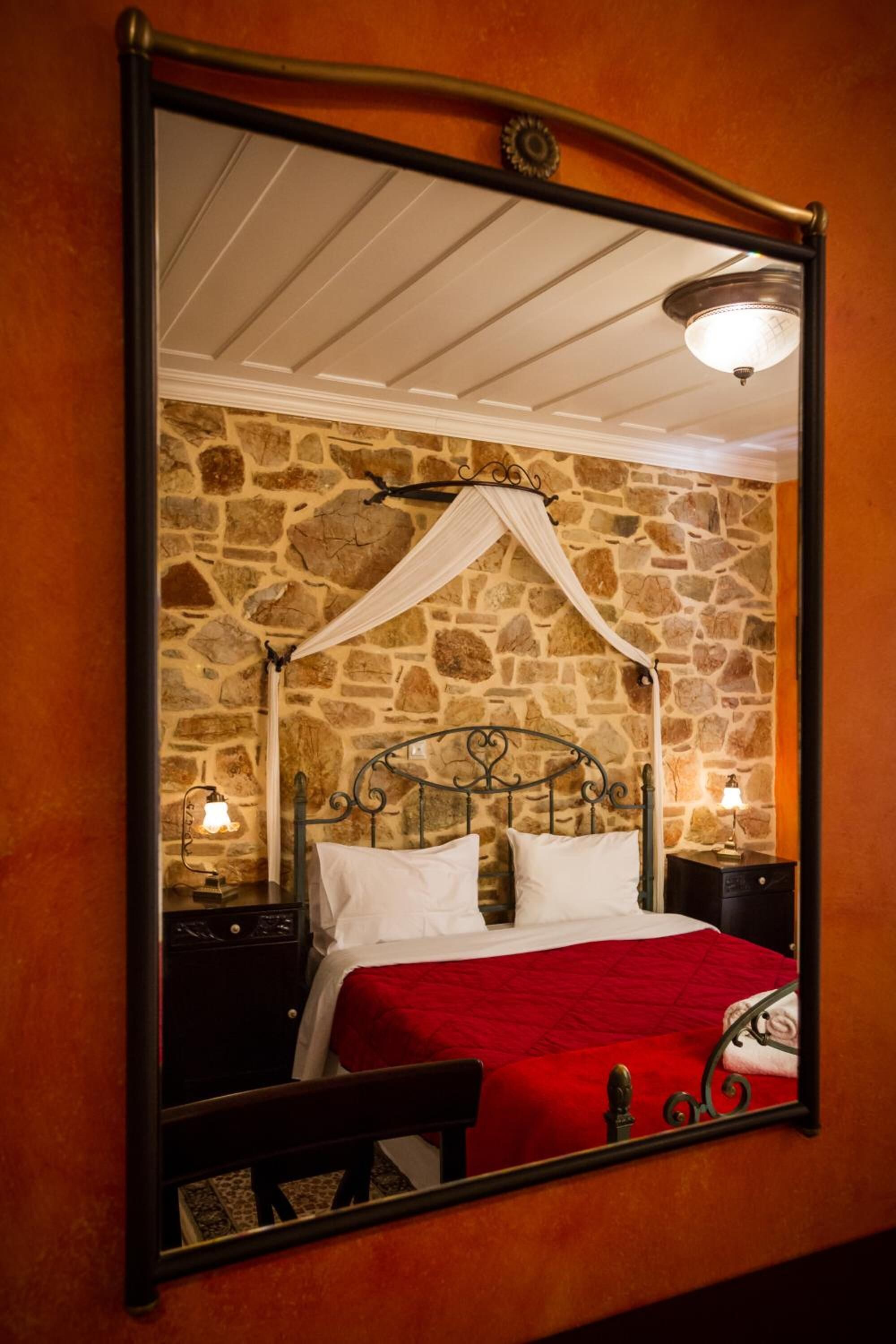 A bed with a stone wall backdrop, a canopy, and bedside lamps.