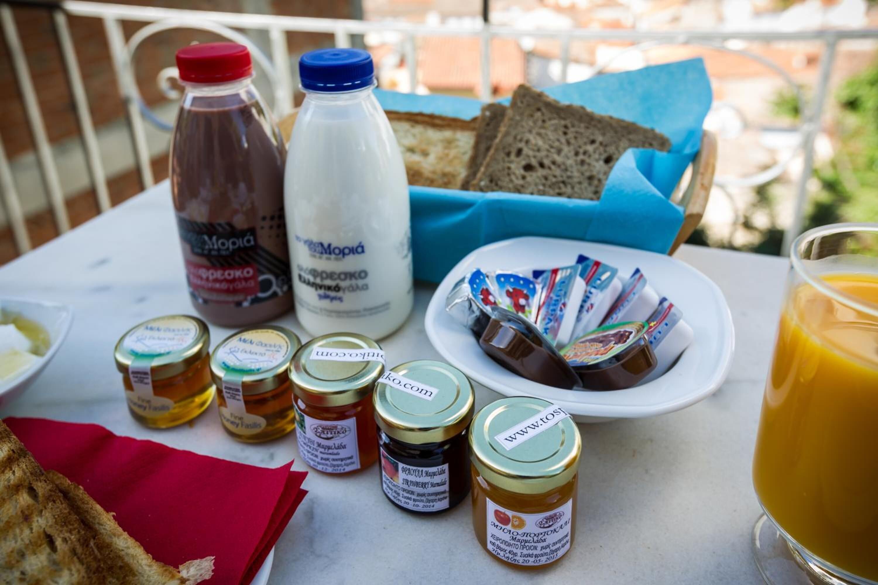 A table with various food items including bread, jars of honey, and a glass of juice.