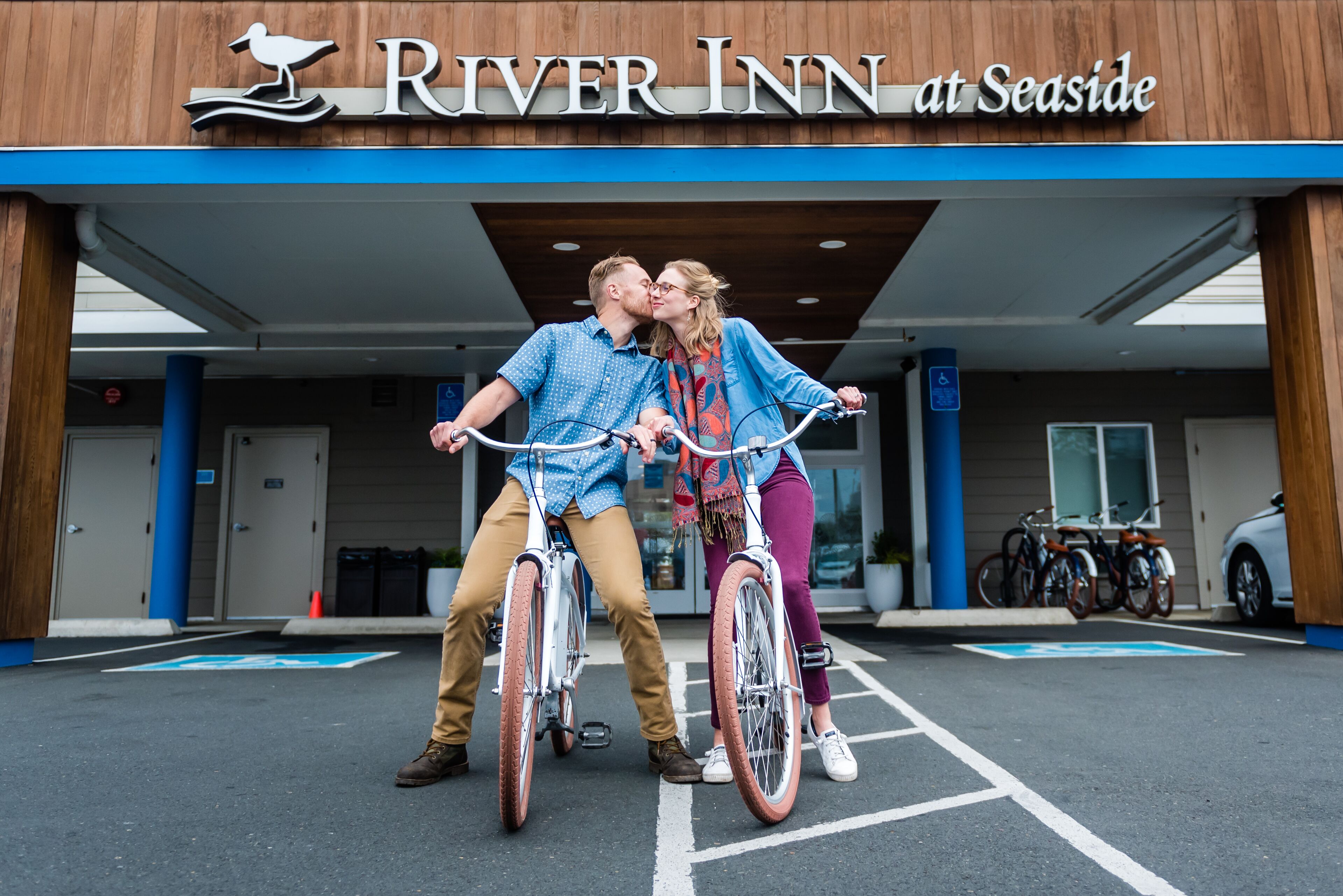 A couple on bicycles in front of the River Inn at Seaside.