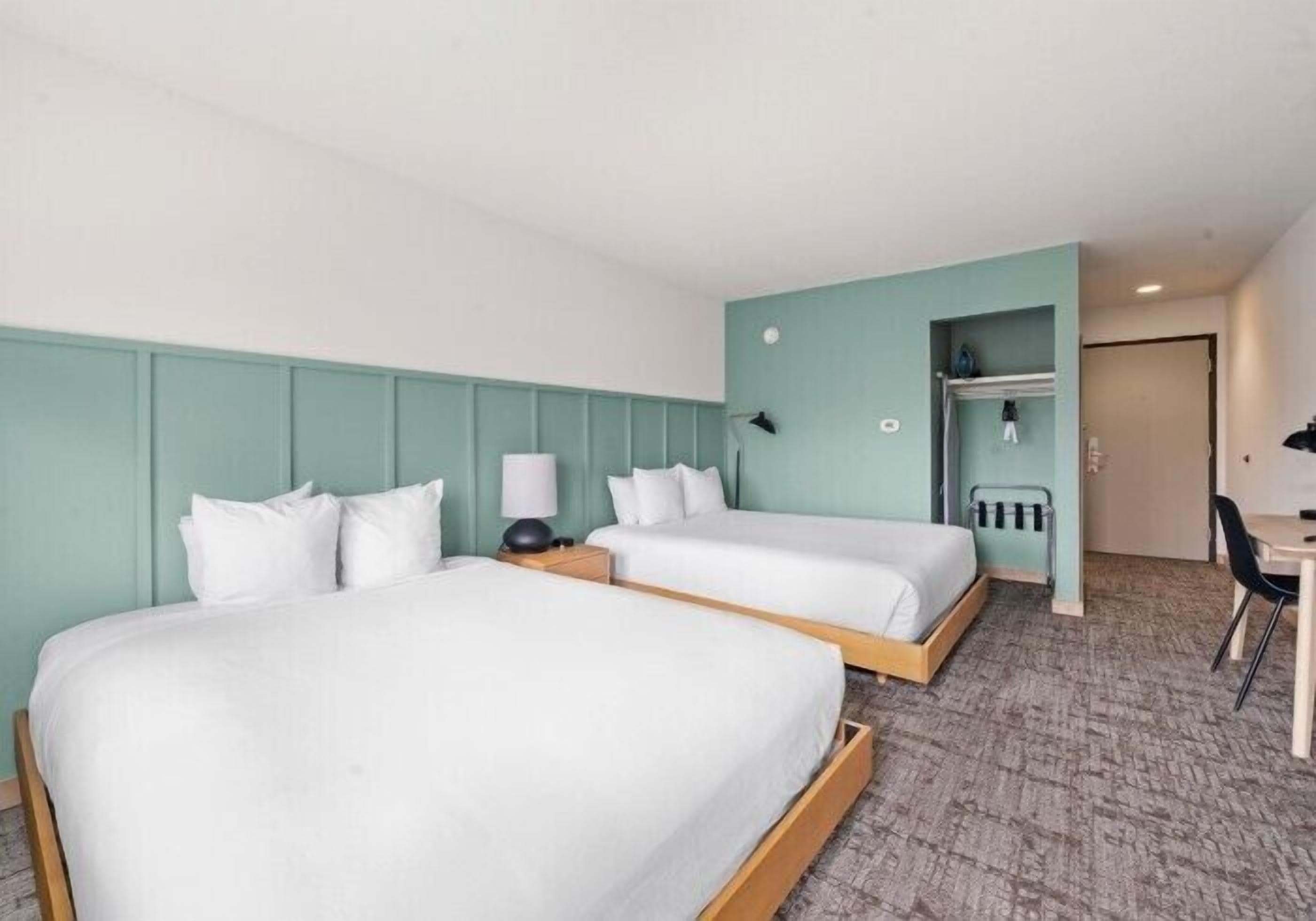 Habitación de hotel con dos camas, un escritorio y una silla.