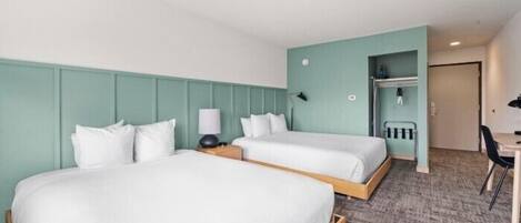 Habitación de hotel con dos camas, un escritorio y una silla.