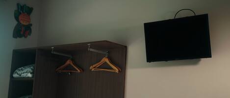 Un placard avec deux cintres en bois, un téléviseur fixé au mur et un objet décoratif accroché au mur.