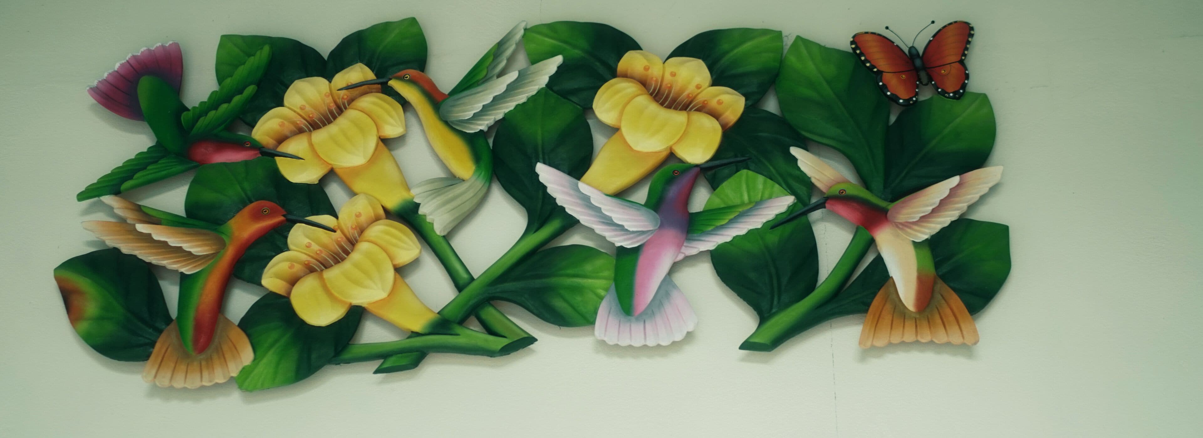 A wall with a mural of birds, flowers, and butterflies.