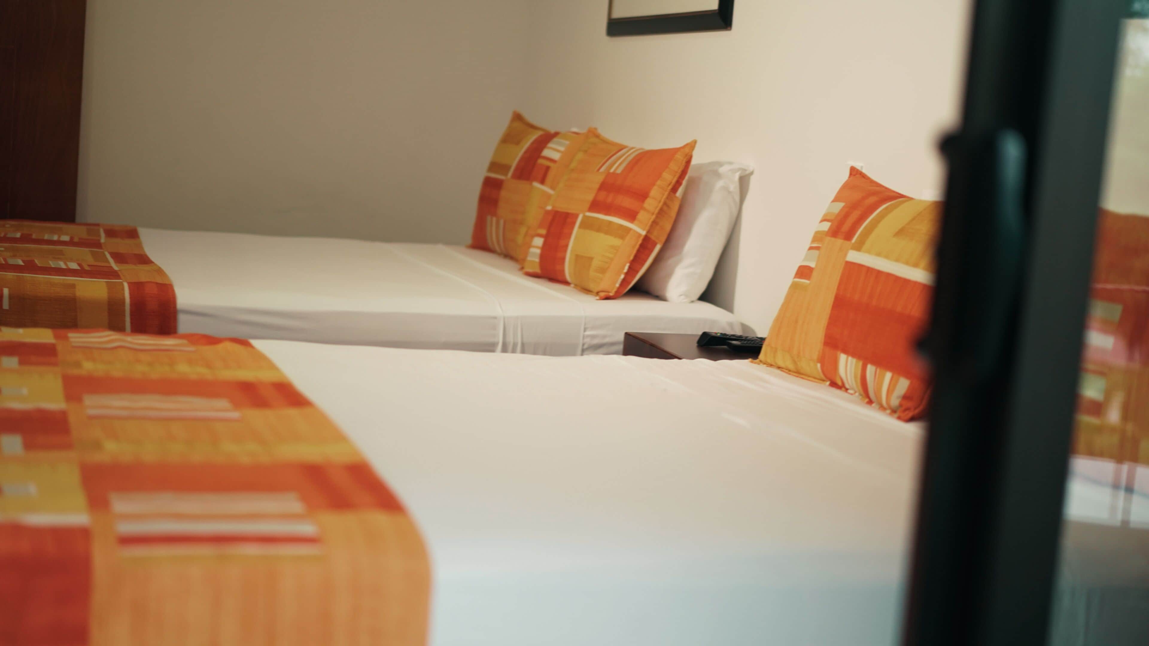 Een hotelkamer met twee eenpersoonsbedden, elk met een beddengoed met een patroon en kussens.