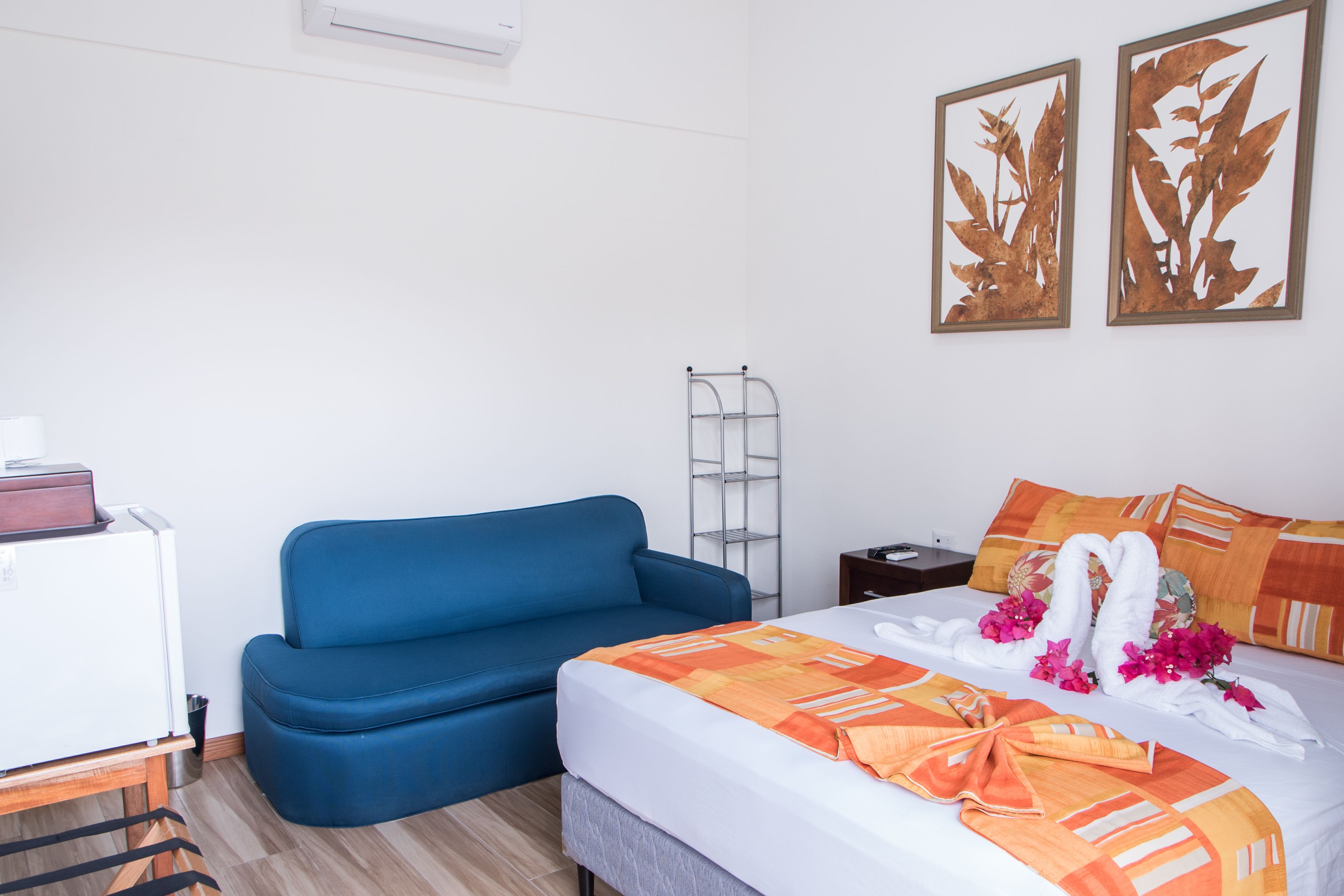 Ein Hotelzimmer mit einem Bett, einem blauen Sofa, einem kleinen Tisch und einem Wandregal.