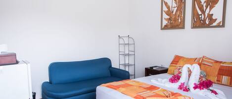 Ein Hotelzimmer mit einem Bett, einem blauen Sofa, einem kleinen Tisch und einem Wandregal.