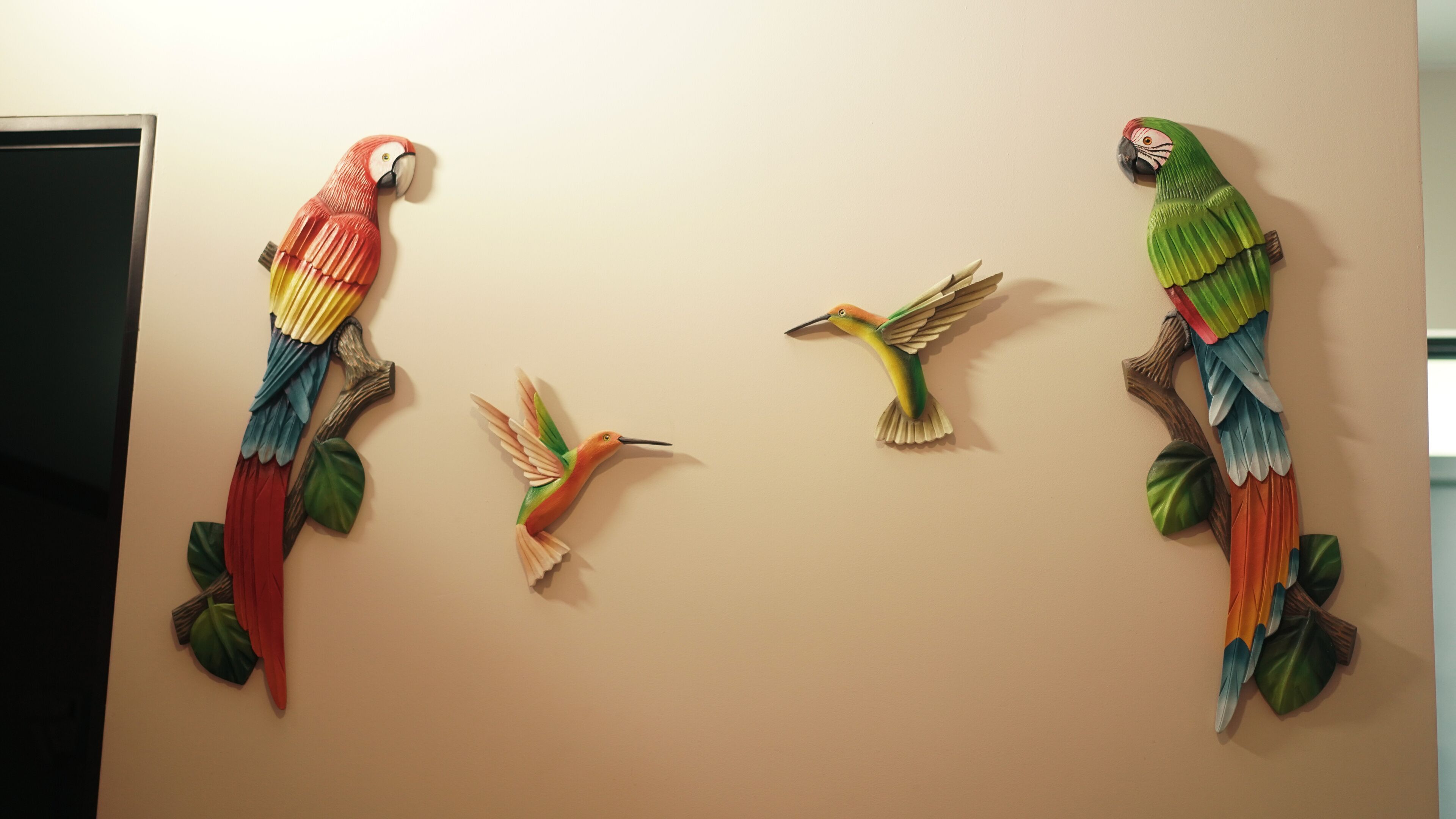 A wall with four colorful bird sculptures.