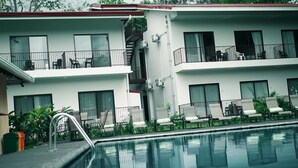 Un hotel con piscina, diversi balconi e zone relax all'aperto.