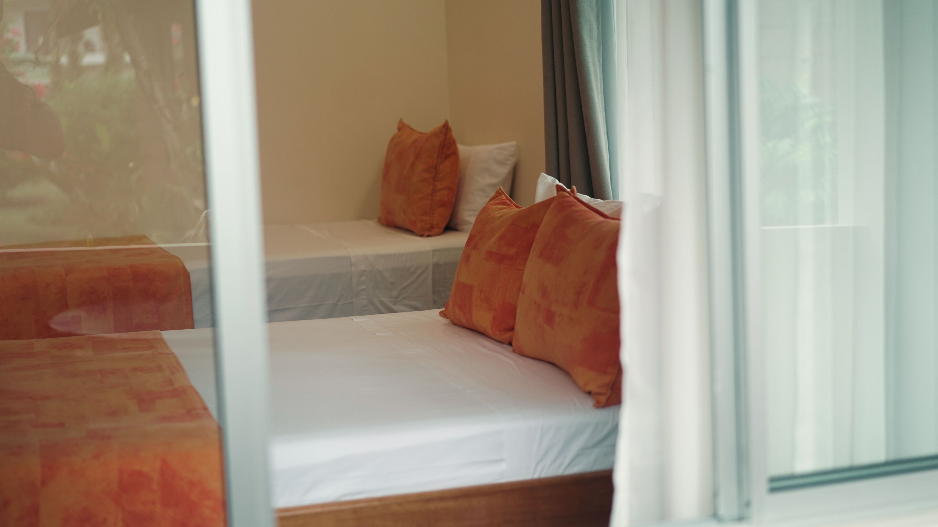 Una habitación de hotel con cama, un banco y una ventana con cortinas.